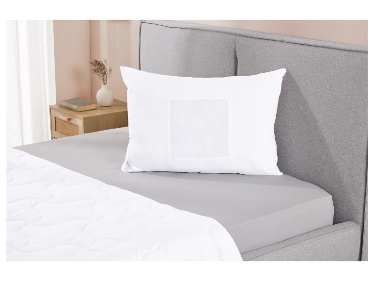 Oreiller blanc sur un lit gris avec une couette.