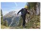 Un homme en veste et pantalon de randonnée marche sur un sentier de montagne.