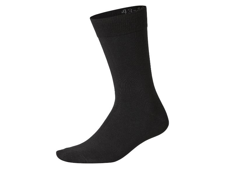 Une chaussette noire unie, posée verticalement sur un fond blanc.