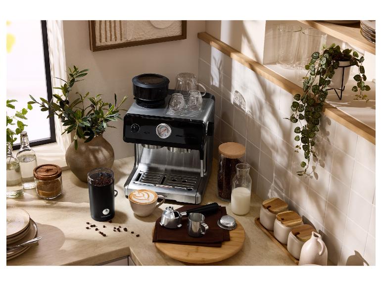 Comptoir de cuisine avec machine à expresso, moulin à café, tasses et grains de café.