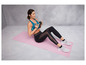 Une femme fait des exercices abdominaux avec une haltère sur un tapis de yoga rose.