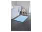 Un tapis de bain bleu clair dans une salle de bain avec une baignoire.
