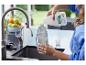 Une personne verse un nettoyant multi-surfaces dans une bouteille de mélange dans la cuisine.