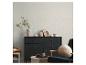Salon moderne avec une commode bleu foncé, un vase avec des branches et un fauteuil.