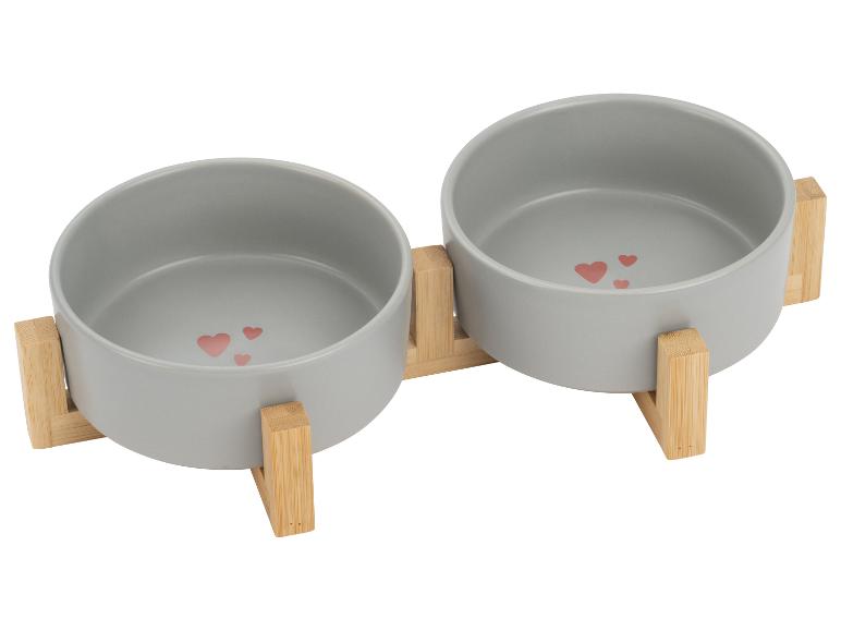 Gamelles doubles grises pour animaux de compagnie avec motif cœurs, sur un support en bambou.