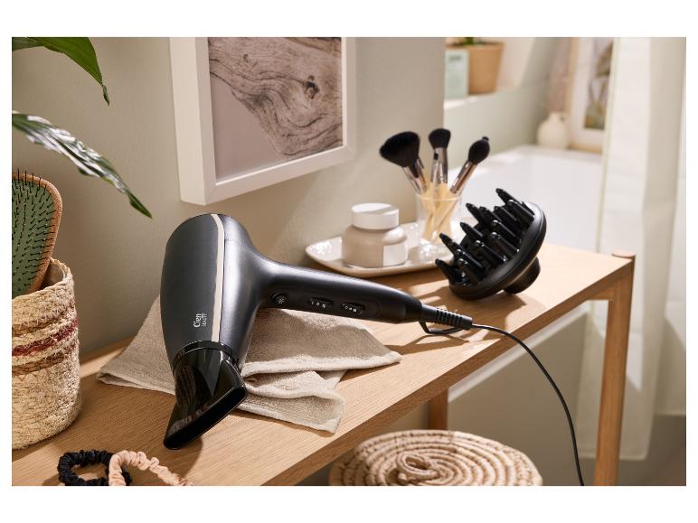 Sèche-cheveux et diffuseur sur une table en bois avec accessoires de beauté dans une salle de bain.