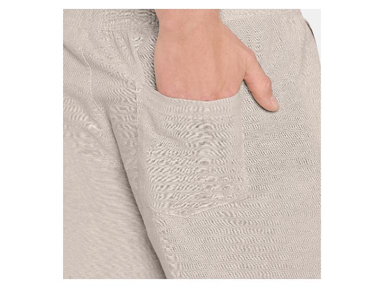 Gros plan d'un pantalon homme en lin beige avec une main dans la poche.