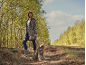 Femme en veste imprimé léopard et chien en gilet assorti sur un chemin forestier.