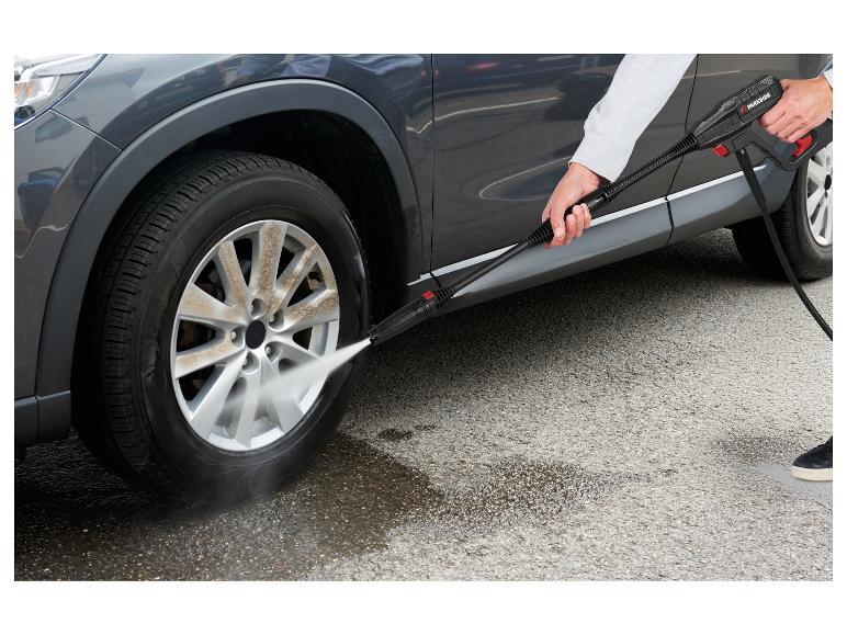 Personne lavant la jante sale d'une voiture avec un nettoyeur haute pression.
