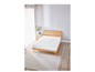 Un matelas blanc sur un cadre de lit en bois avec un tapis à côté.
