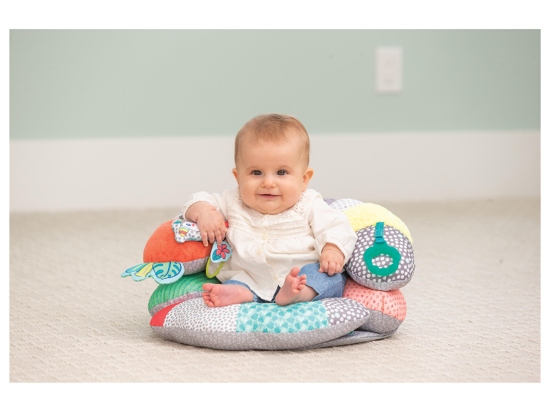 Bébé assis sur un coussin d'assise Tiny Love.