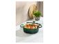 Cocotte verte avec rôti de viande et légumes sur un comptoir en marbre.