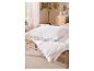 Oreiller et couette blancs sur un banc en bois dans une chambre douillette.