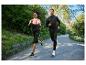 Un couple de coureurs en tenue de sport courant sur un chemin dans un parc.