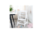 Chaise haute blanche pour bébé avec plateau et harnais de sécurité, à côté d'une table avec bol et tasses.