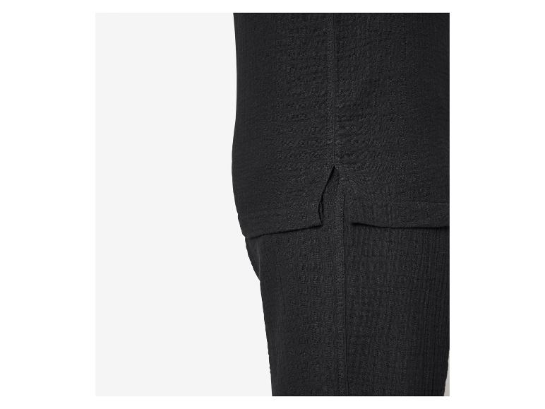 Gros plan d'un tissu noir texturé avec une fente latérale et un détail de couture.