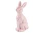 Lapin de Pâques décoratif rose pâle, assis, avec des détails de fourrure sculptés.