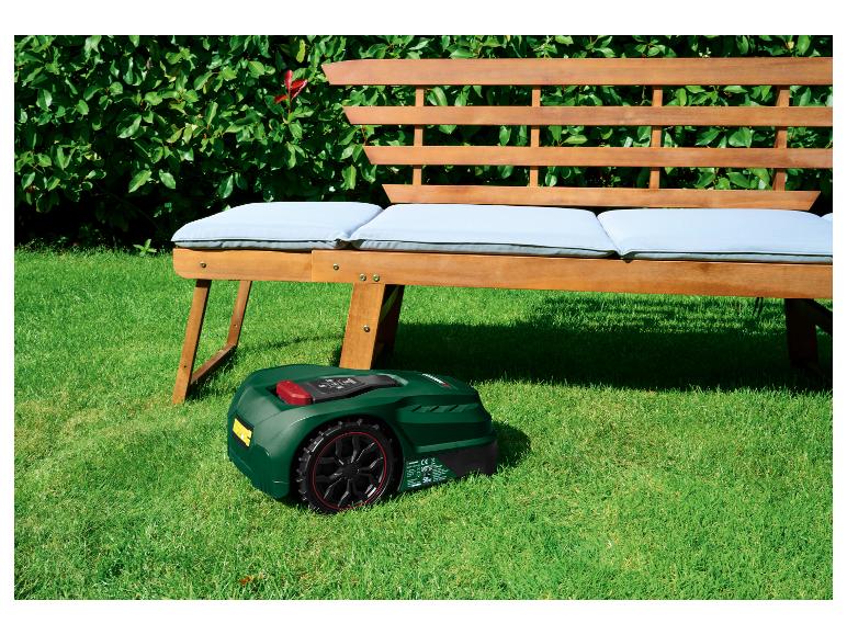 Robot tondeuse Parkside devant un banc en bois avec coussins dans un jardin.