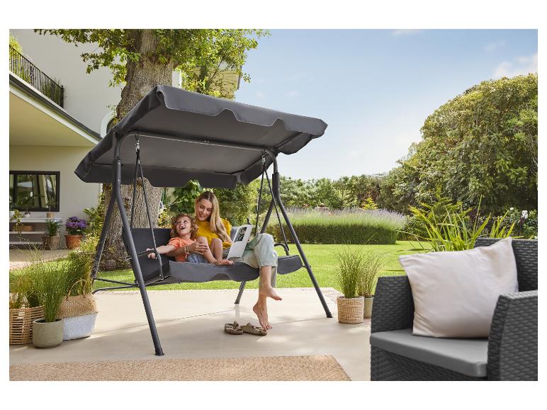 Mère et enfant se balançant sur une balançoire de jardin avec auvent sur une terrasse.