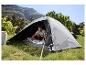 Homme dans une tente de camping se préparant à dormir, avec un paysage de montagne en arrière-plan.