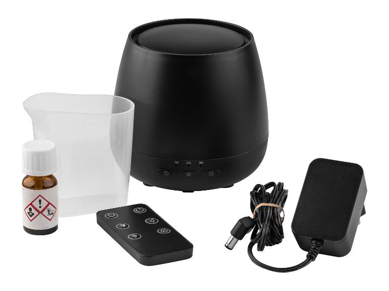 Diffuseur d'arômes noir avec télécommande, verre doseur, huile essentielle et adaptateur secteur.