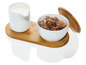 Un pichet à lait blanc et un sucrier avec des morceaux de sucre bruns sur un dessous de plat en bambou.