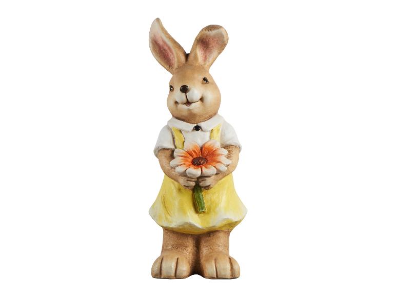 Une figurine de lapin de Pâques avec une robe jaune et une fleur.