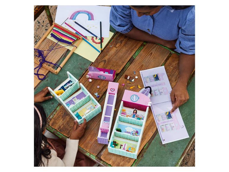 Deux filles construisent un ensemble LEGO Friends sur une table en bois avec des dessins et du tissage.