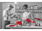 Couple dans la cuisine préparant le petit-déjeuner avec grille-pain, bouilloire et mixeur rouges.