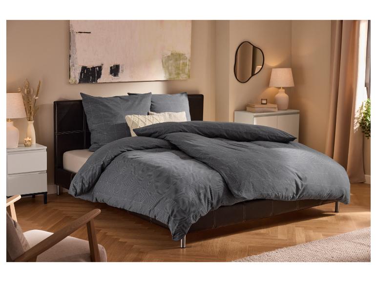 Chambre moderne avec lit rembourré, parure de lit grise à motifs géométriques et tables de chevet blanches.