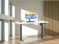 Un bureau blanc avec un piétement noir, un moniteur et un clavier dans une pièce moderne.