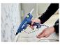 Personne utilisant un pistolet à colle bleu Rapid PRO EG340 pour fixer un câble le long d'un mur.