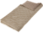Couverture matelassée beige pliée avec motif, partiellement ouverte pour montrer l'envers.