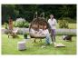 Couple dans un fauteuil suspendu dans le jardin avec mobilier et plantes.