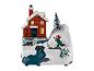 Décoration de Noël avec une maison rouge, un enfant qui joue avec des boules de neige et un sapin de Noël.