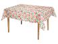 Nappe avec un motif floral rose vif sur fond vert clair, drapée sur une table en bois.
