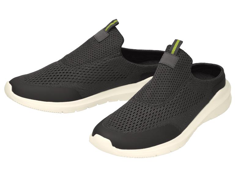 Une paire de chaussures de sport noires sans lacets avec des accents verts et des semelles blanches.