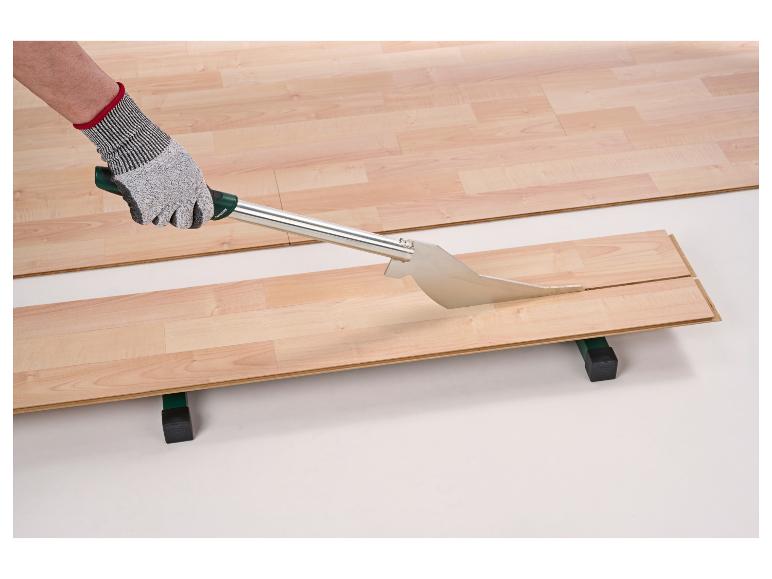 Un ouvrier coupe une planche de stratifié avec un coupe-stratifié.