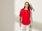 Une femme en haut rouge et pantalon blanc.