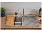 Évier de cuisine avec planche à découper en bois, robinet et égouttoir sur un plan de travail en bois.