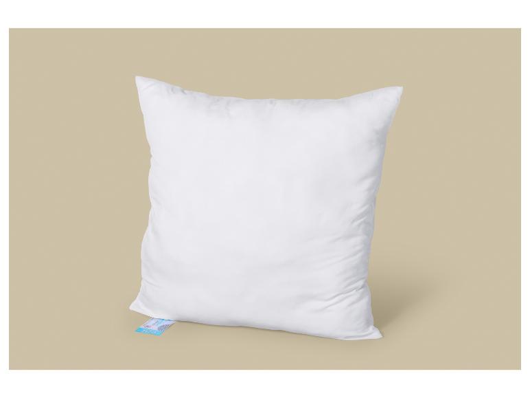 Un oreiller blanc doux avec une étiquette bleue visible en bas.
