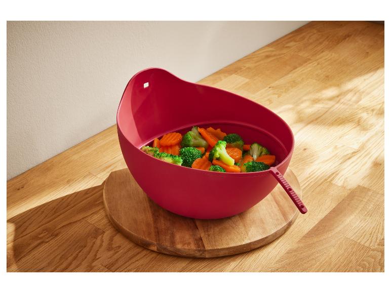 Salade rouge en plastique avec des légumes cuits sur une surface en bois.