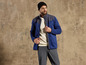 Un homme porte une veste en polaire bleue et un pantalon gris.