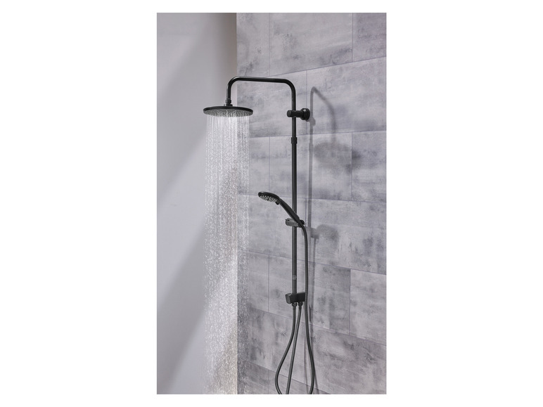 Pomme de douche noire avec douche de pluie et douchette à main contre un mur en béton.