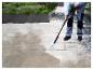 Une personne utilise un nettoyeur haute pression Parkside pour nettoyer une terrasse.