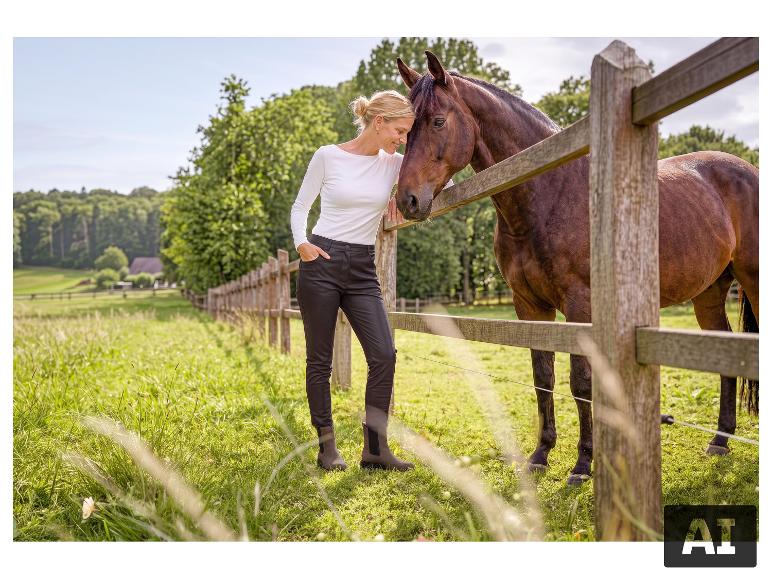 Femme en pantalon slim ESMARA® debout près d'une barrière avec un cheval. [image générée par l'IA]