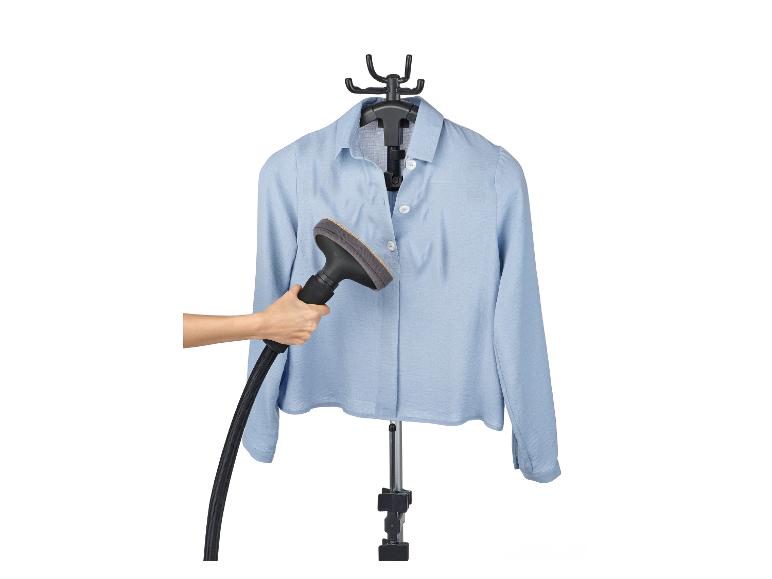 Une femme repasse une chemise bleu clair avec un steamer à main.