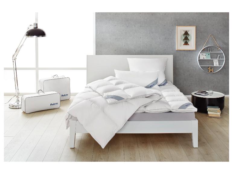 Chambre à coucher avec lit blanc, couettes et oreillers Balette, lampadaire et table d'appoint.