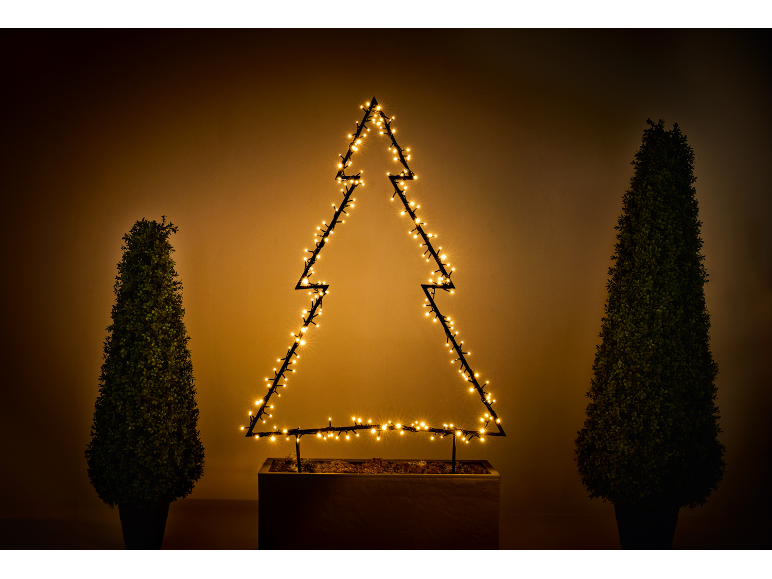 Silhouette d'arbre de Noël illuminée avec deux arbres topiaires en pot.