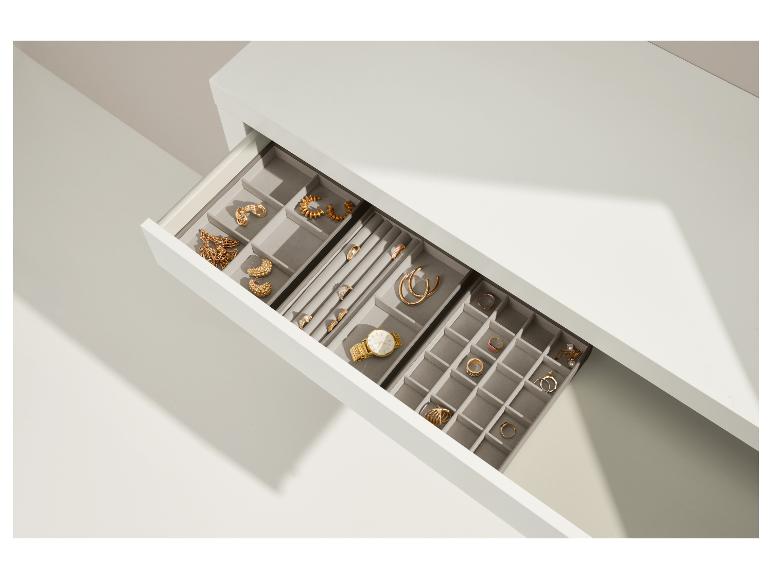 Tiroir ouvert avec organisateur de bijoux, colliers, boucles d'oreilles, bagues et montre dorés.